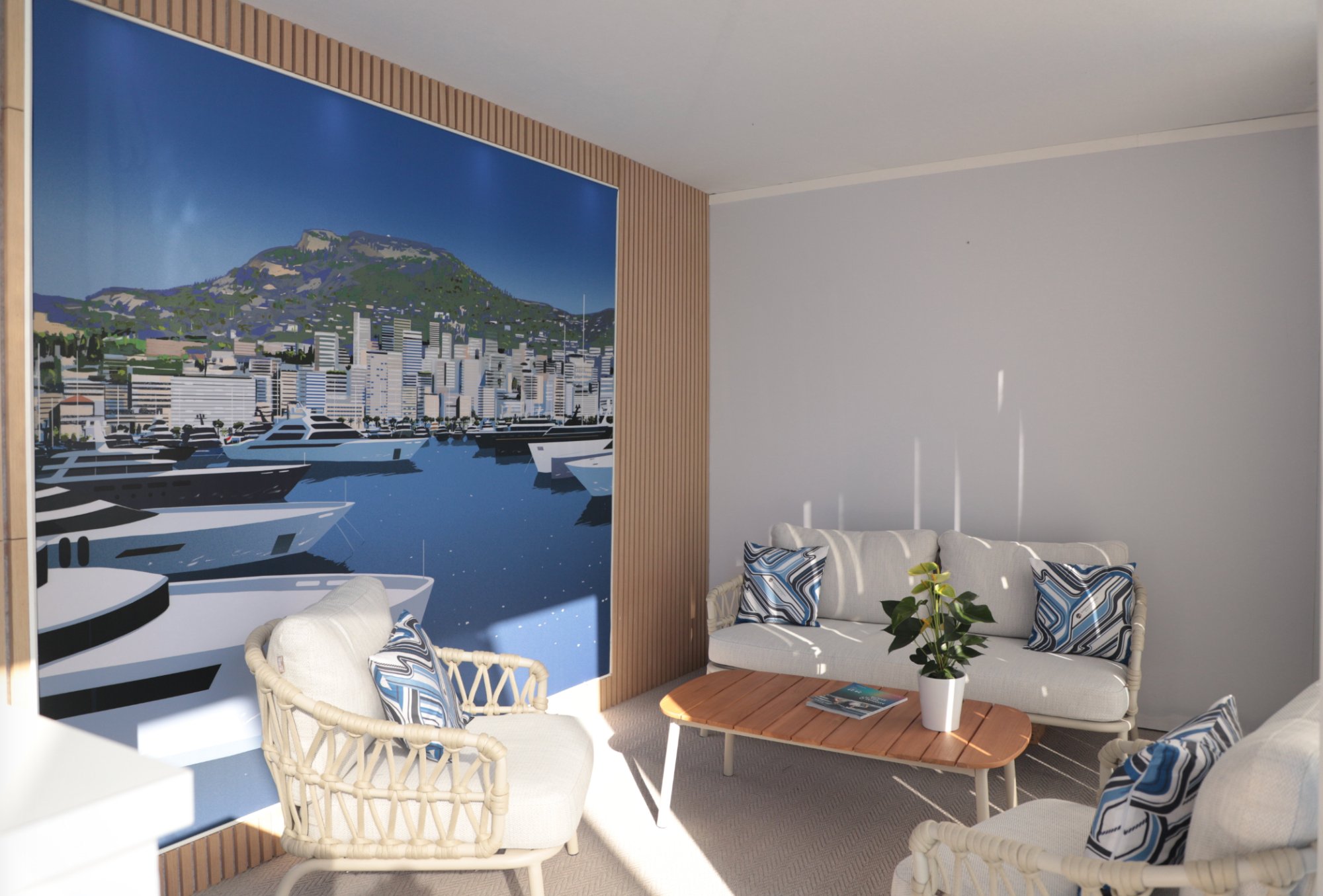 SuperYachtsMonaco stand interior — lounge seating area with Port Hercule illustration backdrop